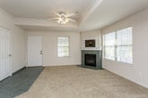 This single-story home offers a thoughtfully designed layout with a bright, open feel throughout. The living room serves as a central gathering space, featuring plush neutral carpeting, a tile-surround fireplace, and multiple windows that allow natural light to fill the room. A ceiling fan overhead adds both comfort and style. The entry door, fitted with glass panels, further enhances the sense of openness.

The kitchen is positioned adjacent to the living area in an open-concept arrangement, separated by a raised breakfast bar with a stone-look countertop. White cabinetry, including glass-front upper cabinets, pairs with white appliances and recessed lighting to create a clean, functional workspace. Dark tile flooring in this area provides a clear visual transition from the carpeted living spaces.

The bedrooms are carpeted and generously proportioned, each equipped with ceiling fans and natural light from windows with outdoor views. Select bedrooms feature tray ceilings with crown molding detailing, adding architectural interest. Closet space is well provided, with one bedroom offering both a walk-in closet and an additional built-in shelving closet.

Both bathrooms are finished with large-format gray tile flooring, tub-shower combinations with sliding glass doors, and vanities featuring stone-look countertops with undermount sinks and wood-trimmed cabinetry. The overall ambiance of the home is neutral, clean, and move-in ready.