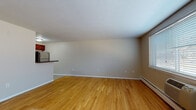 Located at 1250 Farmington Ave in West Hartford, CT, this single-floor unit offers a practical and comfortable layout designed to maximize livability. The main living area is defined by warm, light-toned hardwood flooring that extends throughout, neutral-toned walls, and a large window fitted with blinds that allows natural light to fill the space. A wall-mounted air conditioning unit and baseboard heating ensure year-round climate control.

The kitchen is positioned adjacent to the living area, separated by a raised breakfast bar that creates an open, connected feel. Rich, dark-stained cabinetry is paired with dark granite-style countertops, providing ample storage and prep space. Stainless steel appliances, including a dishwasher, over-the-range microwave, and electric range, complete the kitchen. The flooring transitions to tile in this area.

The bathroom is clean and well-appointed, featuring tile flooring, a white vanity with cabinet storage, a mirrored medicine cabinet, and a full tub-shower combination with tiled surround. A closet with bifold doors is also present, providing additional storage within the unit.