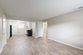 This single-floor unit offers a straightforward, functional layout with a clean and modern aesthetic throughout. The open living area flows directly into the kitchen, both finished with light-toned luxury vinyl plank flooring that lends a bright, cohesive feel to the shared space. Neutral gray walls and crisp white trim are consistent throughout, creating a calm and move-in-ready atmosphere.

The kitchen is well-equipped, featuring white cabinetry that extends to the ceiling for ample storage, a stainless steel sink, a gas range, and a black refrigerator. A window above the back door brings in natural light, enhancing the clean, functional design of the space.

The bedrooms are carpeted in a warm beige tone and feature multiple windows that allow generous natural light to filter in, offering views of the surrounding greenery. The rooms provide comfortable, versatile spaces suited for a variety of furniture arrangements.

The bathroom is finished with white tile surrounding a full tub-shower combination, complemented by a window that adds ventilation and light. Chrome fixtures complete the clean, utilitarian design.

An entry door with a panel design provides a clear threshold from the outside. Throughout the unit, consistent neutral tones, practical finishes, and an efficient use of space define the overall character of this well-maintained property.
