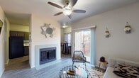 This thoughtfully designed single-floor residence offers a comfortable and cohesive living experience. The living room serves as the heart of the home, showcasing a tile-surround fireplace, wood-look flooring, and a ceiling fan overhead. Natural light flows in generously through a sliding glass door that opens onto a private outdoor patio, blending indoor and outdoor living seamlessly. The space is complemented by neutral wall tones and tasteful wall art, creating a warm and inviting atmosphere.

Adjacent to the living area, a dining nook with bold patterned curtains adds a stylish accent. The kitchen is efficiently laid out with gray cabinetry, white quartz-style countertops, a classic subway tile backsplash, a double stainless steel sink with a modern gooseneck faucet, and black appliances — all set on durable wood-look flooring.

The bedroom is a restful retreat, featuring plush carpeting, a ceiling fan, and a window dressed with decorative curtains that allow for both privacy and natural light.

The bathroom is finished with large-format dark tile in the shower-tub surround, wood-look flooring, and sleek gray cabinetry, offering a clean, contemporary aesthetic throughout.