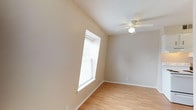 This single-floor property in Maplewood offers a clean, functional layout with a neutral color palette throughout. The living area features wall-to-wall carpeting, a textured ceiling, and direct access to the entry door, providing a welcoming and practical space. Multiple bedrooms are present, each outfitted with ceiling fans with light fixtures and windows fitted with blinds that allow for natural light and ventilation. One bedroom showcases light hardwood flooring and a vaulted-style ceiling, adding a touch of architectural character, while the remaining bedrooms feature soft carpeting underfoot. The kitchen is efficiently designed with white cabinetry, laminate countertops, a coil-burner electric range, a refrigerator, and hardwood-style flooring, making it a practical space for everyday cooking. The bathroom includes a full tub-shower combo with white tile surround, a window for natural light, and standard fixtures. Consistent warm beige tones on the walls and white trim throughout the home create a cohesive, move-in-ready aesthetic. The mix of hardwood-style and carpeted floors across different rooms adds variety and comfort to this straightforward, well-maintained Maplewood property.