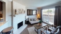 Located on Westheimer Road in Houston, Texas, this two-story residence offers a well-designed layout with thoughtfully appointed spaces throughout. The living area serves as the heart of the home, highlighted by a striking white-painted brick fireplace with a classic mantle, wood-style flooring, crown molding, and a large window that invites natural light. Adjacent to the living area, the kitchen features dark cabinetry with a tile backsplash, light countertops, a built-in dishwasher, and a stainless steel sink — combining practicality with a clean aesthetic. Multiple carpeted bedrooms are spread across both floors, each equipped with ceiling fans, natural light from windows with blinds, and generous closet space. The bedrooms offer a calm, neutral palette with soft gray walls. The bathrooms are finished with dark wood vanities, light countertops, and framed mirrors. One bathroom includes a shower-tub combination, while another features a separate vanity area. A carpeted staircase with wall sconce lighting connects the two floors. Overall, the residence presents a comfortable and cohesive design with a neutral color scheme, wood-style and carpeted flooring, and functional spaces throughout.
