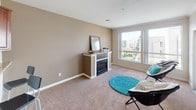 Located at 225 Logan Ave S in Renton, Washington, this single-floor residence offers a thoughtfully designed layout that balances comfort and functionality. The living room serves as a central gathering space, featuring plush wall-to-wall carpeting, warm neutral-toned walls, and a built-in fireplace with a clean mantle surround. A large window floods the room with natural light while framing views of the surrounding neighborhood.

The bedroom is generously proportioned, finished with soft carpeting, crown molding, and a wide sliding window that brings in additional natural light and outdoor views of adjacent architectural details. A closet with bifold doors provides convenient built-in storage.

The entryway transitions seamlessly between spaces, connecting the carpeted living areas to the kitchen via light hardwood-style flooring. The kitchen is well-equipped and features rich, dark wood cabinetry, granite-style countertops with a breakfast bar, and a full suite of stainless steel appliances including a refrigerator, electric range with overhead microwave, and dishwasher. The open pass-through design connects the kitchen to the main living area, enhancing the sense of openness throughout the unit. Crown molding and clean white trim add a polished finish throughout the space.