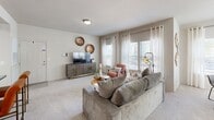This single-story, 2-bedroom, 2-bathroom residence offers a thoughtfully designed layout that maximizes every square foot of living space. The open-concept kitchen is a functional centerpiece, featuring white shaker cabinetry, dark countertops, stainless steel appliances including a French door refrigerator, a kitchen island with seating, and light wood-look tile flooring. A skylight overhead enhances the brightness of the space. The living room is generously sized with plush carpeting and multiple windows dressed in sheer white curtains and horizontal blinds, inviting abundant natural light and outdoor views. The adjacent dining area mirrors this sun-drenched quality, with a wrap-around window arrangement that creates an airy, connected feel. The primary bedroom offers comfortable proportions, soft carpet, a ceiling fan, natural light from a window with curtains, and direct access to additional rooms. The second bedroom shares a similar design sensibility. Both bathrooms are finished with clean white tile, over-tub shower configurations, and built-in cabinetry for storage. A dedicated laundry area with tile flooring and utility connections adds everyday convenience. Throughout, the residence maintains a cohesive, neutral palette that creates a warm and inviting atmosphere.