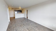 Located at 4351 15th Ave S in Seattle's Columbia City neighborhood, Unit 402 is a thoughtfully designed residential unit offering a clean, modern aesthetic. The open-concept living area is anchored by light gray wood-style flooring that runs throughout, creating a cohesive and inviting atmosphere. Neutral, warm-toned walls complement the airy feel of the space, while track lighting adds both functional illumination and a contemporary touch.

The kitchen is seamlessly integrated into the living space via a raised peninsula counter, ideal for casual dining or entertaining. Dark cabinetry provides a striking contrast against stainless steel appliances, including a refrigerator, microwave, and range, giving the kitchen a polished, modern look. Overhead, additional track lighting ensures the cooking area is well-lit.

The open layout provides generous living and dining space, offering flexibility in furniture arrangement. A doorway leads to the private areas of the unit, maintaining a clear separation between living and sleeping quarters. The overall design emphasizes functionality and modern simplicity, making this single-floor unit a comfortable and stylish residence in Seattle.