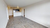 Located at 4351 15th Ave S in Seattle's Columbia City neighborhood, Unit 402 is a thoughtfully designed residential unit offering a clean, modern aesthetic. The open-concept living area is anchored by light gray wood-style flooring that runs throughout, creating a cohesive and inviting atmosphere. Neutral, warm-toned walls complement the airy feel of the space, while track lighting adds both functional illumination and a contemporary touch.

The kitchen is seamlessly integrated into the living space via a raised peninsula counter, ideal for casual dining or entertaining. Dark cabinetry provides a striking contrast against stainless steel appliances, including a refrigerator, microwave, and range, giving the kitchen a polished, modern look. Overhead, additional track lighting ensures the cooking area is well-lit.

The open layout provides generous living and dining space, offering flexibility in furniture arrangement. A doorway leads to the private areas of the unit, maintaining a clear separation between living and sleeping quarters. The overall design emphasizes functionality and modern simplicity, making this single-floor unit a comfortable and stylish residence in Seattle.