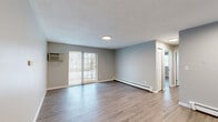 Located at 357 Newport Ave in Quincy, MA, this two-bedroom, one-bathroom residence offers a practical and comfortable single-floor layout. The open living room is bright and inviting, featuring wood-style laminate flooring, soft neutral gray walls, and sliding glass doors that lead to a private balcony, filling the space with natural light. A wall-mounted air conditioning unit and baseboard heating ensure year-round comfort. The adjoining kitchen is well-appointed with warm honey-toned wooden cabinetry, dark granite-style countertops, and a full suite of stainless steel appliances including a gas range, refrigerator, and dishwasher. A breakfast bar adds additional counter space and casual dining convenience. Both bedrooms continue the wood-style flooring and neutral color palette, with multiple windows providing ample natural light. The primary bedroom includes a closet, while both rooms offer baseboard heating. The full bathroom is cleanly finished with white tile, a tub-shower combination, a vanity with storage, and mosaic tile flooring. The overall design is clean, functional, and cohesive, making this a well-organized and move-in-ready residence in the heart of Quincy.