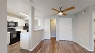 Located at 2665 S Moore Dr in Lakewood, Colorado, this single-floor, one-bedroom, one-bathroom home offers a well-organized and functional layout. The living room serves as the heart of the space, featuring a tiled wood-burning fireplace flanked by multiple windows that fill the room with natural light. Wood-look laminate flooring runs throughout the main living areas, lending a clean, modern feel. A ceiling fan with a built-in light fixture adds comfort and character to the open area connecting the living and dining spaces. The kitchen is thoughtfully designed with white cabinetry, light countertops, a breakfast bar peninsula, and black appliances including a refrigerator, range, and dishwasher. A dedicated pantry provides additional storage just off the kitchen. The bedroom is carpeted for comfort, offering a quiet retreat with a window for natural light and direct access to a generously sized walk-in closet equipped with dual hanging rods. A second closet provides additional storage. The full bathroom features wood-look flooring, a white vanity with a single sink, and a tub-shower combination. An in-unit laundry area completes this practical and comfortable home. Textured ceilings are present throughout, consistent with the building's construction style.