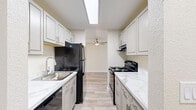 Located in Lynnwood, WA, this 2-bedroom, 1-bathroom single-floor home offers a well-designed layout with modern updates throughout. The galley-style kitchen is a standout feature, showcasing grey shaker cabinets, marble-look countertops, black appliances including a refrigerator and electric range, a stainless steel sink, and a skylight that floods the space with natural light. A ceiling fan is visible just beyond the kitchen, enhancing airflow into the main living area.

The open living area transitions from light wood-look flooring near the kitchen to plush carpeting in the lounge zone, creating a comfortable and functional space. A window looks out to the surrounding greenery, adding a natural element to the interior. The primary bedroom is a well-proportioned retreat with carpet flooring and a window framing outdoor views, while the second bedroom features a sliding glass door opening to an outdoor space, bringing in abundant natural light.

The full bathroom includes a tub/shower combo and wood-look tile flooring. A dedicated laundry area accommodates a stacked GE washer and dryer unit with additional shelf storage. A separate closet provides further storage convenience. Neutral tones and clean finishes give the entire home a bright, move-in-ready feel.