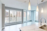 Located in Edmonton's vibrant Oliver neighbourhood, this modern 2-bedroom, 1-bathroom unit offers a thoughtfully designed open-concept layout finished with light hardwood flooring throughout. The combined kitchen and living area is a standout feature, bathed in natural light streaming through expansive floor-to-ceiling windows that frame urban views of the surrounding cityscape. A sliding glass door leads to a private balcony, further enhancing the bright and airy atmosphere.

The kitchen is well-appointed with two-tone cabinetry — white uppers paired with dark wood lower cabinets — complemented by a white quartz countertop, subway tile backsplash, stainless steel appliances including a full-size refrigerator and range, and elegant pendant lighting above the island peninsula.

Both bedrooms are generously proportioned, each benefiting from large windows with city views and light hardwood flooring. The primary bedroom includes a built-in closet, while the second bedroom also features closet storage. The bathroom is finished with marble-style wall surrounds encasing a full soaker tub and tub surround, paired with clean white fixtures. The unit is completed by a dedicated entrance, offering a practical and welcoming arrival experience.