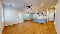Located at 7808 E 161st Pl S in Bixby, Oklahoma, this two-story home offers four bedrooms, three bathrooms, and a thoughtfully designed layout spread across two floors. The main floor comprises the majority of the living space and features an open-concept living room, dining area, and kitchen. The kitchen is a standout space, showcasing light gray shaker-style cabinetry, a large center island with a white quartz countertop and sink, stainless steel appliances, subway tile backsplash, and striking geometric pendant lights over warm hardwood-style flooring. The dining area is bathed in natural light from a bank of windows and accented by a modern chandelier. A dedicated office provides flexible workspace on the main level. The upper floor hosts additional bedrooms, each with plush carpeting, ceiling fans, and ample natural light. Walk-in closets with built-in shelving provide generous storage. The three bathrooms include tiled tub-shower combinations with modern black hardware accents. A spacious attached garage with an automatic opener and electrical panel access adds convenience. Outside, the board-and-batten exterior leads to a fenced backyard with a patio, offering a private outdoor retreat.