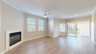 This single-floor residence offers a thoughtfully designed layout with a clean, contemporary aesthetic throughout. The open living area is finished with light wood-look flooring, crown molding, and a ceiling fan, creating a bright and airy atmosphere. Multiple windows fitted with blinds allow natural light to fill the space, while a sliding glass door leads to a private balcony overlooking a lush, tree-lined exterior. A corner fireplace adds a functional focal point to the living room.

The galley-style kitchen is well-equipped with gray shaker cabinetry, quartz countertops, a deep undermount sink with a professional-style faucet, stainless steel appliances including a double oven range and refrigerator, a wall-mounted range hood, and a classic white subway tile backsplash. Light wood-look flooring continues seamlessly from the living areas into the kitchen.

Bedrooms feature plush carpeting, ceiling fans, and generous closet space, including a walk-in closet in the primary bedroom, which also connects to a private bathroom. The bathroom includes a soaking tub and shower combination with a curved curtain rod. A dedicated laundry area accommodates a full-size washer and dryer. Neutral tones and consistent finishes unify the space throughout.