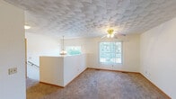 Located at 216 N Kendall Ave in Kalamazoo, Michigan, this two-floor residence offers a practical and comfortable layout. The main living area is a standout feature, showcasing a distinctive scalloped textured ceiling, a ceiling fan with light fixture, warm neutral carpeting, and a half-wall divider with a pendant light. Multiple windows dressed with vertical blinds flood the space with natural light and offer views of the surrounding greenery.

The kitchen is equipped with warm oak cabinetry featuring arched detailing, a double-basin sink, light countertops, a gas range, a dishwasher, and tile flooring — providing ample storage and functional workspace. A louvered door leads to additional storage or utility space nearby.

The bedrooms are carpeted and bright, each featuring vertical-blind-covered windows that bring in abundant natural light. The rooms offer clean, neutral walls with wood-toned baseboards, providing a versatile canvas for personalization.

The bathroom includes a full tub-shower combo, a single-sink vanity with cabinetry, a large mirror with overhead lighting, and tile flooring, maintaining a clean and functional design throughout.

Overall, the home presents a well-maintained, functional interior with consistent finishes across both floors, suited for comfortable everyday living in a residential Kalamazoo neighborhood.