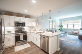 Located at 2930 Rockaway Ave in Oceanside, NY, this one-bedroom, one-bathroom residence offers a thoughtfully designed single-floor layout with modern finishes and a bright, welcoming ambiance. The open-concept kitchen is a standout feature, outfitted with crisp white shaker cabinetry, a white subway tile backsplash, stainless steel appliances including a gas range, microwave, and dishwasher, and a peninsula with a double-basin sink and quartz-style countertops. Stylish pendant lighting in a brushed brass finish adds warmth to the space. The kitchen flows seamlessly into the living area, which is bathed in natural light from large windows overlooking the surrounding neighborhood. Soft blue-gray walls and warm wood-tone flooring carry throughout, creating a cohesive and calming aesthetic. The bedroom is generously proportioned, featuring two closets—including a walk-in—and a bright window that enhances the airy feel. The bathroom is finished with white subway tile, a white vanity with a gray countertop, and chrome fixtures, offering a clean and polished look. Overall, this residence combines functional design with contemporary style in a well-lit, comfortable living environment.