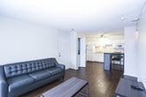 This single-story unit offers a practical and straightforward layout across several rooms. The living area features dark hardwood-style flooring and neutral walls, with a sliding glass door fitted with vertical blinds that allows natural light to filter in and provides access to the outdoors. A textured ceiling and floor-level vents complete the space.

The kitchen is equipped with white cabinetry, light laminate countertops, and a full suite of white appliances including a refrigerator, electric range, built-in microwave, and dishwasher. A ceiling fan overhead provides ventilation, and the dark flooring carries through from the living area, creating visual continuity.

Multiple bedrooms are carpeted and feature textured ceilings, offering a softer feel underfoot. Each room includes closet space with sliding doors, and windows allow for natural light. The rooms are modestly sized and well-suited for functional furnishing arrangements.

The bathrooms each feature a white tub and shower combination with chrome fixtures, a built-in soap ledge, and a grab bar, set against clean white surround walls. The overall aesthetic throughout the unit is neutral and clean, emphasizing functionality.