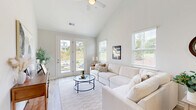Located at 317 Hart Townes Way in Woodruff, SC, this two-story home offers a thoughtfully designed layout across two floors. The main level provides a generous footprint anchored by an open-concept living, dining, and kitchen area. The living room features soaring vaulted ceilings, light wood-look flooring, and large windows alongside French doors that flood the space with natural light and provide direct access to the outdoors. The kitchen is outfitted with white shaker cabinetry, granite countertops, a stainless steel refrigerator, and a multi-seat breakfast bar that flows seamlessly into the dining area. Upstairs, the primary bedroom showcases vaulted ceilings, a ceiling fan, plush carpeting, and natural light from well-placed windows. Its en-suite bathroom features a dual-sink vanity with white cabinetry, a glass-enclosed shower, and light wood-look tile flooring. Two additional bedrooms offer comfortable carpeted spaces with ample natural light and closet access, including a spacious walk-in closet with wire shelving. A full bathroom with a tub/shower combo serves the secondary bedrooms. A dedicated laundry room with a full-size washer and dryer completes the home's practical offerings. Neutral tones and clean finishes throughout lend the home a bright, modern ambiance.