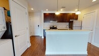 Located at 130 W 44th St in Bayonne, NJ, this single-floor residence is thoughtfully designed with modern finishes throughout. The kitchen is a standout feature, equipped with rich dark-espresso cabinetry, light quartz countertops, a mosaic tile backsplash, and a full suite of stainless steel appliances including a gas range, microwave, and refrigerator. Pendant lighting over the kitchen island adds a warm, inviting glow, while recessed lighting illuminates the space throughout.

Rich hardwood flooring extends through the main living and kitchen areas, creating a cohesive and polished aesthetic. The open living area is generously proportioned and benefits from large sliding glass doors that invite abundant natural light and offer views of the surrounding Bayonne neighborhood. Bedrooms are finished with plush carpeting and feature double-door closets for ample storage.

Two bathrooms serve the residence: one with a glass-enclosed walk-in shower and dark vanity cabinetry, and a second with a full soaking tub, tile surround, and matching vanity. A dedicated in-unit laundry closet with a stacked washer and dryer provides added convenience. The overall ambiance is clean, contemporary, and move-in ready.