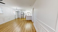 Located at 4015 Estermarie Dr in Cincinnati, OH, this thoughtfully designed two-bedroom unit offers a clean, modern aesthetic across a single floor. Warm hardwood-style flooring runs throughout the entire space, creating a cohesive and inviting atmosphere from room to room.

The open-concept kitchen and living area serves as the heart of the home. The kitchen is outfitted with crisp white shaker-style cabinetry featuring matte black hardware, a white quartz countertop, a black undermount sink, and a full suite of stainless steel appliances including a refrigerator, dishwasher, range, and microwave. A central island provides additional prep and dining space. An elegant globe chandelier anchors the living area, which is accented by decorative wainscoting panels along the walls.

Both bedrooms are bright and airy, each featuring natural light from blinded windows and ceiling fans with integrated lighting. The primary bedroom offers a comfortable footprint and includes a sliding door, while the second bedroom features a distinctive white-painted brick accent wall and coordinating wainscoting details, adding textural character to the space.

A connecting hallway provides practical flow between the rooms. The overall design is clean, minimal, and move-in ready, reflecting a consistent modern-neutral palette throughout.
