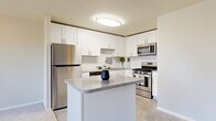 Located at 2746 Belmont Ave in Philadelphia's 19131 zip code, this one-bedroom, one-bathroom unit offers a practical and well-appointed layout across a single floor. The open-concept kitchen and living area serves as the heart of the home, featuring a modern kitchen outfitted with crisp white shaker cabinetry, granite-style countertops, a central island, and a full suite of stainless steel appliances including a refrigerator, gas range, microwave, and dishwasher. The kitchen flows seamlessly into the spacious living room, which is carpeted and bathed in natural light through two large windows dressed with vertical blinds. A baseboard heating unit ensures year-round comfort. The generously sized bedroom offers plush carpeting, a large window with outdoor views, and a built-in closet with bi-fold doors providing ample storage. The bathroom is clean and functional, featuring full white subway tile surrounding a soaking tub and shower combination, with tile flooring. A dedicated laundry area adds everyday convenience. Throughout the unit, neutral tones and clean finishes create a bright, move-in-ready atmosphere.