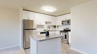 Located at 2746 Belmont Ave in Philadelphia's 19131 zip code, this one-bedroom, one-bathroom unit offers a practical and well-appointed layout across a single floor. The open-concept kitchen and living area serves as the heart of the home, featuring a modern kitchen outfitted with crisp white shaker cabinetry, granite-style countertops, a central island, and a full suite of stainless steel appliances including a refrigerator, gas range, microwave, and dishwasher. The kitchen flows seamlessly into the spacious living room, which is carpeted and bathed in natural light through two large windows dressed with vertical blinds. A baseboard heating unit ensures year-round comfort. The generously sized bedroom offers plush carpeting, a large window with outdoor views, and a built-in closet with bi-fold doors providing ample storage. The bathroom is clean and functional, featuring full white subway tile surrounding a soaking tub and shower combination, with tile flooring. A dedicated laundry area adds everyday convenience. Throughout the unit, neutral tones and clean finishes create a bright, move-in-ready atmosphere.