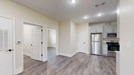 Located in Houston, TX, this single-story 2-bedroom, 2-bathroom home offers a clean, modern aesthetic with consistent wood-look flooring and warm neutral tones throughout. The open kitchen and living area serve as the heart of the home, showcasing a well-designed kitchen with gray shaker-style cabinetry, granite-look countertops, a full suite of stainless steel appliances including a refrigerator, range, microwave, and dishwasher, all complemented by recessed lighting above. Both bedrooms are comfortably proportioned, featuring ceiling fans, natural light from window panels with blinds, and generous closet space — the primary bedroom includes a double-door closet. The two bathrooms maintain the same cohesive design language, with gray shaker vanities, granite-look countertops, and wood-look flooring. The full bathroom features large-format gray tile surrounding a soaking tub and shower combo. Throughout the home, crisp white baseboards and trim provide clean contrast against the warm beige walls, contributing to a bright and well-finished interior that feels both functional and move-in ready.