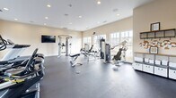 Located at 1881 SS Railroad Bed Rd in Statesboro, Georgia, this fitness center offers a well-appointed, single-floor exercise facility designed to support a comprehensive workout experience. The space is finished with neutral, warm-toned walls and durable dark rubber flooring, creating a clean and functional environment throughout.

Large multi-pane windows line the walls, flooding the interior with abundant natural light while providing views of the surrounding neighborhood. Recessed ceiling lighting further ensures the space remains consistently bright at all times of day.

The fitness center is outfitted with a diverse selection of equipment, including multiple treadmills, a cable crossover machine, a functional trainer, and a variety of selectorized strength machines suited for both upper and lower body workouts. A wall-mounted flat-screen television is positioned for visibility from the cardio equipment area, enhancing the workout experience.

A full-length mirror along one wall visually expands the space and allows users to monitor their form during exercise. Built-in cabinetry and shelving provide organized storage for accessories and supplies. An exit door and a windowed interior door offer convenient access points within the layout.

The overall design balances practicality and comfort, making this fitness center a well-rounded amenity for residents of the community.