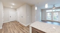 This thoughtfully designed one-bedroom, one-bathroom unit in Charlotte, NC offers a modern and cohesive interior with quality finishes throughout. The open-concept layout connects the kitchen and living areas seamlessly, creating an efficient and inviting flow.

The kitchen is a standout feature, showcasing warm taupe cabinetry, a classic white subway tile backsplash, and a full suite of stainless steel appliances, including a range, dishwasher, and French door refrigerator. A central island topped with granite countertops provides additional prep space and casual seating, illuminated by a trio of pendant lights. Durable hardwood-style flooring runs throughout the main living areas, complementing the neutral color palette.

The bedroom is a comfortable retreat, carpeted for warmth and featuring a ceiling fan, a large window with outdoor views, and access to a dedicated closet. Natural light fills the room, creating a bright and airy atmosphere.

The bathroom is finished with a granite-topped vanity with dark cabinetry, wood-style flooring, and a full tub-shower combination equipped with safety grab bars and a tub bench, reflecting a thoughtful, accessible design.

A dedicated closet and convenient hallway layout round out this well-planned unit, offering practical living in a clean, modern setting.