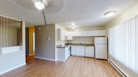 Located at 4440 E Pikes Peak Ave in Colorado Springs, Colorado, this single-floor unit offers a straightforward, functional layout designed for comfortable everyday living. The open-concept kitchen and living area form the heart of the space, connected by light wood laminate flooring that runs consistently throughout. The kitchen is well-equipped with white cabinetry extending to the upper walls for ample storage, granite-look countertops in an L-shaped configuration, a white electric range, dishwasher, refrigerator, and a stainless steel sink. A textured ceiling and ceiling fan with a light fixture add to the practical character of the space. Large windows fitted with vertical blinds allow natural light to fill the living area, which also features a baseboard heating unit along the exterior wall. A secondary room, suitable as a bedroom, mirrors the clean aesthetic with matching flooring, a ceiling fan, and a window with vertical blinds. The bathroom is tiled in classic white, featuring a full soaking tub with a shower, chrome fixtures, and a towel bar. The overall ambiance is clean, neutral, and move-in ready, providing a solid foundation for personalization in a convenient Colorado Springs location.