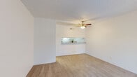 Located at 1975 W 36th St in Tucson, Arizona, this single-floor, 2-bedroom, 1-bathroom unit offers a practical and efficient layout across a compact footprint. The living room is carpeted and filled with natural light from a large window fitted with vertical blinds, and is equipped with a ceiling fan with light fixture. A textured ceiling adds character throughout the common areas. A distinctive pass-through counter with a granite-style surface connects the living room to the kitchen, creating an open feel between the two spaces. The galley-style kitchen features wood-look vinyl plank flooring, white cabinetry on both sides, a double-basin sink, and white appliances including a refrigerator, electric range, and dishwasher, providing ample functionality in a compact corridor layout. Both bedrooms are carpeted and finished with neutral white walls; each receives natural light through windows. The primary bedroom is comfortably sized and features its own closet. The shared bathroom includes wood-look vinyl flooring, a white vanity with granite-style countertop, a mirrored medicine cabinet, and a full shower-tub combination. A hallway connects the main living areas to the bedrooms and bathroom, completing this well-organized floor plan.