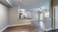 This single-floor residence opens through a tiled entryway equipped with a thermostat and intercom panel, setting a functional tone from the start. The open-concept living and dining area is defined by warm hardwood-style flooring, crown molding, and a ceiling fan with light fixture. Natural light filters through blinded windows, and a pass-through granite countertop connects the living space to the kitchen, enhancing the open feel.

The kitchen is well-appointed with gray cabinetry, granite countertops, a subway tile backsplash, and a full suite of stainless steel appliances including a range, microwave, dishwasher, and refrigerator. Crown molding and wood-look flooring continue throughout.

The bedrooms are generously sized, each featuring hardwood-style flooring, ceiling fans, and windows with exterior views. Six-panel doors and neutral walls maintain a clean, cohesive aesthetic throughout.

The bathrooms are finished with granite-topped vanities, gray cabinetry, wood-look flooring, and tub/shower combinations featuring large-format tile surrounds and brushed nickel fixtures, offering a polished, uniform design.