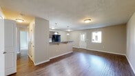Located at 6185 E Medalist Ln in Nampa, Idaho, this single-story unit offers a well-designed, functional layout with a cohesive blend of modern finishes throughout. The open-concept living and dining area is anchored by rich hardwood-style flooring that extends toward a peninsula-style kitchen, which features dark countertops, dark cabinetry with wood-tone upper cabinets, pendant lighting, and black appliances including a full-size refrigerator and range. A dedicated walk-in pantry provides generous storage. A textured ceiling adds character to the main living space, which is filled with natural light from front-facing windows. The unit includes multiple bedrooms, some with plush carpeting and large windows that invite natural light, and others with wood-style flooring and closet access. Two full bathrooms are appointed with wood-tone vanities, white countertops, tile-accented surrounds, tub-shower combinations, and windows for natural ventilation. A dedicated laundry room accommodates full-size washer and dryer units with an overhead shelf for additional storage. The overall ambiance is clean, neutral, and move-in ready, with consistent finishes that create a cohesive and practical living environment.