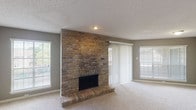 This single-story residence offers a thoughtfully designed layout with two bedrooms and two bathrooms. The spacious living area serves as the centerpiece of the home, anchored by a dramatic floor-to-ceiling brick fireplace with a raised hearth. Neutral-toned carpet, a textured ceiling, and multiple windows with horizontal blinds and vertical panel sliders allow abundant natural light to fill the room. A sliding glass door provides direct outdoor access.

The kitchen features dark espresso cabinetry, granite countertops, black appliances including a refrigerator and range, and a decorative tile backsplash. Wood-look flooring adds warmth and durability to this functional space.

Both bedrooms are carpeted and include ceiling fans with light fixtures and ample window coverage. The primary bedroom boasts mirrored sliding closet doors that enhance the sense of space. The primary bathroom offers an extended vanity with dark cabinetry and a white countertop, complemented by wood-look tile flooring. The secondary bathroom includes a tub-shower combination, matching vanity, and similar flooring. Together, these spaces create a comfortable and cohesive living environment.