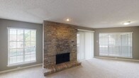 This single-story residence offers a thoughtfully designed layout with two bedrooms and two bathrooms. The spacious living area serves as the centerpiece of the home, anchored by a dramatic floor-to-ceiling brick fireplace with a raised hearth. Neutral-toned carpet, a textured ceiling, and multiple windows with horizontal blinds and vertical panel sliders allow abundant natural light to fill the room. A sliding glass door provides direct outdoor access.

The kitchen features dark espresso cabinetry, granite countertops, black appliances including a refrigerator and range, and a decorative tile backsplash. Wood-look flooring adds warmth and durability to this functional space.

Both bedrooms are carpeted and include ceiling fans with light fixtures and ample window coverage. The primary bedroom boasts mirrored sliding closet doors that enhance the sense of space. The primary bathroom offers an extended vanity with dark cabinetry and a white countertop, complemented by wood-look tile flooring. The secondary bathroom includes a tub-shower combination, matching vanity, and similar flooring. Together, these spaces create a comfortable and cohesive living environment.