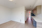 Located on the fourth floor at 521 2nd Ave W in Seattle's Queen Anne neighborhood, this one-bedroom, one-bathroom apartment offers a thoughtfully designed layout that maximizes every square foot. Light wood-tone flooring runs throughout the main living areas, complementing the clean white walls and creating a bright, airy atmosphere.

The combined kitchen and living room serves as the heart of the unit. The kitchen features dark wood cabinetry with warm taupe upper cabinets, a white countertop peninsula with built-in storage drawers, stainless steel appliances, and track lighting overhead — making the space both functional and visually cohesive.

A well-lit hallway connects the living area to the private spaces, with natural light filtering in from a window at the far end. Three closets along the corridor provide generous storage, a notable asset in a compact residence.

The bedroom offers a cozy, well-proportioned retreat with light flooring and a sliding panel closet door, keeping the space uncluttered and open. The bathroom is finished with crisp white walls, a full soaking tub and shower combo, a wood-toned vanity, and warm yellow resilient flooring, lending a clean and functional character.

Overall, the unit presents a modern, minimalist aesthetic well-suited for urban living in Seattle.