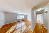 Located at 21 Baldwin Path in Deer Park, NY, this two-story home offers a thoughtfully designed layout across two bedrooms, one bathroom, and multiple functional spaces. The main living level is generously proportioned, featuring gleaming hardwood floors that run throughout and large windows that allow natural sunlight to pour in, creating a bright and welcoming atmosphere. Crown molding adds a refined architectural touch to the living room and bedrooms alike.

The kitchen is a standout feature, outfitted with crisp white shaker-style cabinetry extending floor to ceiling, light quartz countertops, a classic white subway tile backsplash, and stainless steel appliances including a refrigerator and electric range with hood — a clean, modern aesthetic throughout.

Both bedrooms are well-sized, with the primary bedroom offering generous square footage, crown molding, hardwood floors, and its own closet. The second bedroom similarly features hardwood floors and closet access. In total, five closets are distributed throughout the home, ensuring abundant storage.

A staircase with warm wood treads and a classic white riser design connects the levels. The home also includes a balcony with outdoor views of the surrounding greenery and parking area. Two hallways and two staircases ensure smooth flow throughout the space.