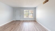 Located at 102 Court Street in Titusville, Florida, this 2-bedroom, 1-bathroom residence offers a clean, modern aesthetic throughout its well-utilized single floor. Light gray walls, crisp white trim, and wood-look plank flooring run consistently through the space, creating a cohesive and contemporary feel.

The open-concept layout seamlessly connects the kitchen, dining, and living areas. The kitchen is a standout feature, outfitted with white shaker cabinetry, granite-look countertops, a subway tile backsplash, and a full suite of stainless steel appliances including a refrigerator, range, and over-the-range microwave. An in-unit washer is also conveniently integrated into the kitchen area. Natural light enters through multiple windows fitted with blinds.

The living area is bright and open, with a window offering outdoor views and a front entry door that brings in additional natural light. Both bedrooms are comfortably sized, with the primary bedroom featuring a louvered double-door closet and ample room to furnish. The unit includes four closets in total, providing generous storage throughout.

The bathroom is clean and functional, finished in white tile with a full bathtub and shower combination and a small window for ventilation. A private balcony extends the living space outdoors, offering views of the surrounding grounds and mature trees.