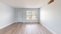 Located at 102 Court Street in Titusville, Florida, this 2-bedroom, 1-bathroom residence offers a clean, modern aesthetic throughout its well-utilized single floor. Light gray walls, crisp white trim, and wood-look plank flooring run consistently through the space, creating a cohesive and contemporary feel.

The open-concept layout seamlessly connects the kitchen, dining, and living areas. The kitchen is a standout feature, outfitted with white shaker cabinetry, granite-look countertops, a subway tile backsplash, and a full suite of stainless steel appliances including a refrigerator, range, and over-the-range microwave. An in-unit washer is also conveniently integrated into the kitchen area. Natural light enters through multiple windows fitted with blinds.

The living area is bright and open, with a window offering outdoor views and a front entry door that brings in additional natural light. Both bedrooms are comfortably sized, with the primary bedroom featuring a louvered double-door closet and ample room to furnish. The unit includes four closets in total, providing generous storage throughout.

The bathroom is clean and functional, finished in white tile with a full bathtub and shower combination and a small window for ventilation. A private balcony extends the living space outdoors, offering views of the surrounding grounds and mature trees.