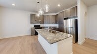 Located at 425 E Foster Crossing Rd in Anna, TX, this single-floor, three-bedroom, two-bathroom home offers a thoughtfully designed layout with consistent finishes throughout. The kitchen serves as a centerpiece of the home, showcasing rich, taupe-toned shaker cabinetry extending to the ceiling, granite countertops, stainless steel appliances, and a large central island with an undermount sink illuminated by elegant globe pendant lights. An arched entryway connects the kitchen area to the hallways, adding an architectural detail that enhances the open feel of the floor plan. Light wood-style flooring runs throughout the home, complementing the neutral wall tones and generous natural light provided by windows in every room. Each of the three bedrooms features a ceiling fan, window with blinds, and clean, minimalist finishes, offering comfortable and versatile living spaces. The primary bathroom includes a granite-topped vanity with dark cabinetry, a full tub-shower combination with white tile surround, and upper storage cabinets. The second bathroom provides a spacious, accessible layout with a walk-in shower, dark wood cabinetry, and a matching granite vanity. Three hallways connect the rooms efficiently, and a dedicated closet adds practical storage. The overall ambiance is clean, modern, and move-in ready.
