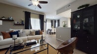 This single-story residence is thoughtfully designed with an open-concept layout that seamlessly connects the living, dining, and kitchen areas. The living room serves as the heart of the home, featuring light wood-style flooring, a ceiling fan, and multiple windows dressed with dark curtains and white blinds that allow for ample natural light. Floating shelves, a glass-top coffee table, and warm neutral wall tones contribute to an inviting, contemporary atmosphere.

The dining area sits adjacent to the living space, benefiting from its own set of large windows that flood the room with natural light. A dark wood dining table paired with white upholstered chairs provides a clean, contrasting aesthetic.

The galley-style kitchen is well-appointed with dark espresso cabinetry, white countertops, and stainless steel appliances, including a range, microwave, refrigerator, and dishwasher, all set atop light wood-style flooring.

The primary bedroom offers a calm retreat with carpeted flooring, a window with blackout draping, and neutral walls. A secondary bedroom provides flexible use as a guest room or office. Both bathrooms mirror the home's design language, featuring dark vanity cabinetry, white countertops, and light flooring, with one offering a shower and the other a shower-tub combination.