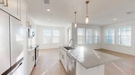 Located at 1700 Ranch Rd in Nokomis, FL, this well-appointed single-story home offers three bedrooms, two bathrooms, and three closets within a thoughtfully designed floor plan. The open-concept kitchen and living area serves as the heart of the home, showcasing white shaker cabinetry, granite countertops, a large center island with an undermount sink, stainless steel appliances, and elegant pendant lighting. Light wood-style flooring flows throughout the main living areas, complemented by crisp white walls and an abundance of natural light streaming through multiple windows with classic white blinds. The spacious living room provides generous room for entertaining and relaxing. The primary bedroom offers a comfortable footprint with a walk-in closet equipped with wire shelving. Additional bedrooms feature plush carpeting, ceiling fans, natural light from large windows, and closet access. Both bathrooms are finished with clean, modern fixtures; one includes a soaking tub and shower combo adorned with large white subway tile. The home's bright, neutral palette and consistent finishes create a cohesive, move-in-ready aesthetic throughout every room.