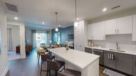 This single-story, one-bedroom, one-bathroom residence in Spring, TX offers a well-designed open-concept layout. The kitchen is a standout feature, equipped with stainless steel appliances—including a French door refrigerator, gas range, and dishwasher—complemented by crisp white cabinetry, quartz countertops, and a spacious island with bar seating. Pendant lighting overhead adds a modern touch, while wood-style flooring runs throughout the main living areas.

The kitchen flows seamlessly into the dining and living areas, where a bold accent wall in deep teal adds visual interest. The living room benefits from natural light through large sliding glass doors that open to a private balcony with outdoor views.

The bedroom is a comfortable retreat featuring plush carpeting, a window with exterior views, and ample space. The full bathroom includes a tub/shower combination with tile flooring and a vanity with storage, and connects directly to a dedicated laundry area with an in-unit washer and dryer.

Overall, the unit presents a contemporary aesthetic with neutral tones, modern finishes, and a functional layout suited for everyday living.