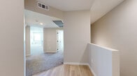 This single-floor home offers a thoughtfully organized layout across four bedrooms and two full bathrooms. The combined kitchen and living room serves as the heart of the home, featuring a bright, modern kitchen outfitted with white shaker-style cabinetry, stainless steel appliances including a gas range, microwave, dishwasher, and refrigerator, a central island with a light countertop, and light wood-look flooring. The living area transitions seamlessly with neutral carpet and a ceiling fan, with a window providing natural light and exterior views. The primary bedroom is a well-proportioned retreat with plush carpeting and a walk-in closet featuring wire shelving for organized storage. A second closet with wire rack shelving serves additional bedrooms. The two bathrooms are finished in a clean, contemporary style — one featuring a full soaking tub and shower combination, and the other a glass-enclosed walk-in shower with a vanity and mirror. Soft, neutral tones in warm beige and white are carried throughout the home, complemented by light hardwood-style flooring in key areas and plush carpet in the bedrooms and living spaces. A hallway and staircase connect the layout, with ceiling vents ensuring comfortable climate control throughout.