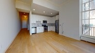 Located at 170 S 6th St in Philadelphia's storied Old City neighborhood, this two-floor residence blends classic architectural character with contemporary interior finishes. The entry hallway sets a welcoming tone with light hardwood flooring, crown molding, and a striking staircase featuring dark metal balusters and white risers that lead to the upper level. Natural light pours in through a large window at the end of the hall, creating an airy, open feel.

The main living area flows seamlessly into a well-appointed kitchen outfitted with white shaker cabinetry, granite countertops, a subway tile backsplash, and a full suite of stainless steel appliances including a gas range, dishwasher, and refrigerator. Light hardwood flooring continues throughout, complementing the recessed lighting overhead.

The upper floor features carpeted bedrooms distinguished by elegant crown molding and architecturally notable arched and fan-shaped windows that serve as striking focal points. Multiple bathrooms are finished with warm wood vanities, stone-topped counters, large-format tile flooring, and a choice of glass-enclosed walk-in showers or soaking tub combinations. Crown molding appears consistently throughout both floors, reinforcing a cohesive, refined aesthetic.
