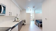 Located at 345 Lincoln Ave in Amherst, Massachusetts, this thoughtfully designed studio offers a smart, modern layout that maximizes every square foot across a single floor. Light wood-tone flooring and crisp white walls flow throughout the space, creating a clean, contemporary aesthetic.

The kitchen is a standout feature, outfitted with a full suite of stainless steel appliances — including a refrigerator, electric range, over-the-range microwave, and dishwasher. Two-tone cabinetry pairs white upper cabinets with warm wood-finish lower cabinets, complemented by white quartz countertops and a sleek black-accented sink. A built-in desk area provides a dedicated workspace within the main living area, while a bed nook with a window offers a defined sleeping zone.

The bathroom is finished in a consistent modern palette, featuring light wood-tone flooring, a wood-finish vanity with white countertop, a large mirror, and clean white walls with chrome fixtures. Ample wall space allows for practical towel storage.

A dedicated in-unit laundry room houses a full-size Whirlpool front-loading washer and dryer side by side, with overhead wire shelving for additional storage. This well-appointed studio combines efficient design with quality finishes throughout.