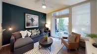 This well-appointed two-floor residence blends contemporary design with practical living across multiple rooms. The living area serves as the heart of the home, anchored by a striking deep teal accent wall adorned with large-scale artwork, hardwood-style flooring, and a ceiling fan. Sliding glass doors flood the space with natural light and open onto a private balcony, creating a seamless indoor-outdoor connection. The kitchen is outfitted with stainless steel appliances including a refrigerator, electric range, and built-in microwave, complemented by white cabinetry, granite countertops, a center island, and open display shelving. The bedrooms offer distinct personalities: the primary bedroom features a rich teal accent wall, plush carpeting, and a window that invites natural light, while a secondary bedroom showcases soft sage-green walls, a built-in closet, and its own window with garden views. Each bedroom includes thoughtful storage solutions such as reach-in closets with built-in shelving and dresser space. The bathrooms are tastefully finished, one featuring a deep teal palette, a wide vanity with a large mirror, and a separate shower, and another with a clean tiled tub-shower combination. Throughout, the space maintains a cohesive modern aesthetic with carefully chosen color accents and functional design.