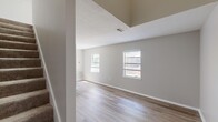 Located on Brookridge Drive SW in Decatur, Alabama, this two-story residence is thoughtfully laid out across two floors. The lower level houses a combined kitchen and living room, designed for efficient use of space. The kitchen is well-appointed with dark gray shaker-style cabinetry, white countertops, a subway tile backsplash, a double-basin sink, and white appliances including an electric range and refrigerator. Light wood-look flooring runs throughout, complementing the neutral gray walls and clean white trim. The living area is bright and open, with multiple windows allowing natural light to fill the room, and features a textured ceiling that adds a subtle layer of visual interest. A staircase connects the lower level to the upper floor, where the bathroom and closet are located. The bathroom is finished with a vanity featuring matching dark gray cabinetry, a round sink, a lighted mirror, and a separate water closet. The closet offers convenient dedicated storage. The upper floor also continues the light wood-look flooring and neutral color palette, maintaining a consistent and clean aesthetic throughout. The overall design is modern, functional, and move-in ready.