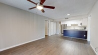 Located in Clearwater, FL, this well-appointed 2-bedroom, 2-bathroom residence offers a thoughtfully designed single-level layout. Wood-look flooring flows throughout the living areas and bedrooms, complemented by neutral gray walls and crisp white trim that create a clean, cohesive aesthetic. Textured ceilings and ceiling fans are found in the living room and both bedrooms, enhancing comfort and airflow.

The open living area connects seamlessly to the kitchen, which is a standout feature of the home. It showcases two-tone cabinetry with rich dark lower cabinets and white upper shaker-style cabinets, white quartz countertops, a subway tile backsplash, and a full suite of stainless steel appliances including a refrigerator, electric range, microwave, and dishwasher. A skylight-style overhead fixture brightens the kitchen further. A bold navy blue peninsula island adds a distinctive design element between the kitchen and living space.

The living room offers sliding glass doors with vertical blinds that invite natural light and provide outdoor access. The primary bedroom is generously sized, featuring two windows, a ceiling fan, and a closet. Both bathrooms are consistently finished with dark espresso vanities, white quartz countertops, and tub-shower combinations.