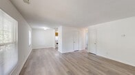 Located at 1 Woodmere Dr in Petersburg, VA, this two-bedroom, one-bathroom single-floor home offers a clean, functional layout with a bright and neutral aesthetic throughout. The open living room is a welcoming space, featuring light-toned luxury vinyl plank flooring, crisp white walls, and multiple windows that invite generous natural light and views of the surrounding greenery. The layout flows naturally from the living area toward the kitchen and bedrooms, providing a practical and easy-to-navigate floor plan. The kitchen is well-appointed with warm honey-toned wood cabinetry, ample upper and lower storage, light countertops, a built-in dishwasher, a gas range, and a refrigerator — all set on matching LVP flooring. Both bedrooms are carpeted for comfort and feature sliding-door closets for storage. The primary bedroom is a generously sized retreat with a large window allowing natural light to fill the room. The full bathroom is finished with tile wainscoting, a wood vanity with white countertop, brushed nickel fixtures, a framed mirror, and stylish lighting. The consistent use of light tones and clean finishes throughout gives this home a bright, move-in ready feel.