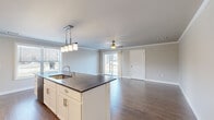 Located at 1110 Alexandra Ln in Harrisburg, PA, this well-appointed single-floor home offers a thoughtfully designed layout across a comfortable footprint. The open-concept kitchen and living area serves as the heart of the home, featuring a large center island with dark granite-style countertops, an undermount sink, and stylish pendant lighting overhead. White shaker cabinetry, a mosaic tile backsplash, and a full suite of stainless steel appliances — including a gas range, built-in microwave, dishwasher, and French door refrigerator — complete the kitchen. The living room is bright and airy, with crown molding, a ceiling fan, sliding glass doors that invite natural light, and hardwood-style flooring throughout. The bedroom is carpeted for comfort, fitted with a ceiling fan, and offers a large window with outdoor views. It connects to a generously sized walk-in closet with wire shelving on multiple walls. The bathroom features clean, neutral finishes with wood-look flooring and modern fixtures. A hallway with additional storage ties the layout together, creating a cohesive and functional living space with contemporary style throughout.