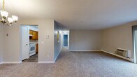 Located at 37 Sharon Rd in Waterbury, CT, this single-floor, two-bedroom, one-bathroom residence offers a comfortable and functional layout. The living room is a bright, open space featuring plush carpeting, neutral-toned walls, and a sliding glass door that opens to a private balcony. The balcony overlooks lush greenery and mature trees, providing a serene outdoor view. A wall-mounted HVAC unit and baseboard heating ensure year-round comfort. A pass-through window connects the living area to the kitchen, which features warm wood cabinetry, creating an open and connected feel between spaces.

The primary bedroom is generously sized, bathed in natural light from two windows with blinds, and equipped with both a wall HVAC unit and baseboard heating. The second bedroom also features carpeted flooring, a window with natural light, and baseboard heating. A dedicated closet provides built-in shelving for organized storage. The full bathroom includes a single-sink vanity with wood cabinetry, a tub-shower combination with classic tile surround, and wood-style flooring. The overall ambiance is clean, neutral, and move-in ready, with greenery views accessible from multiple rooms.